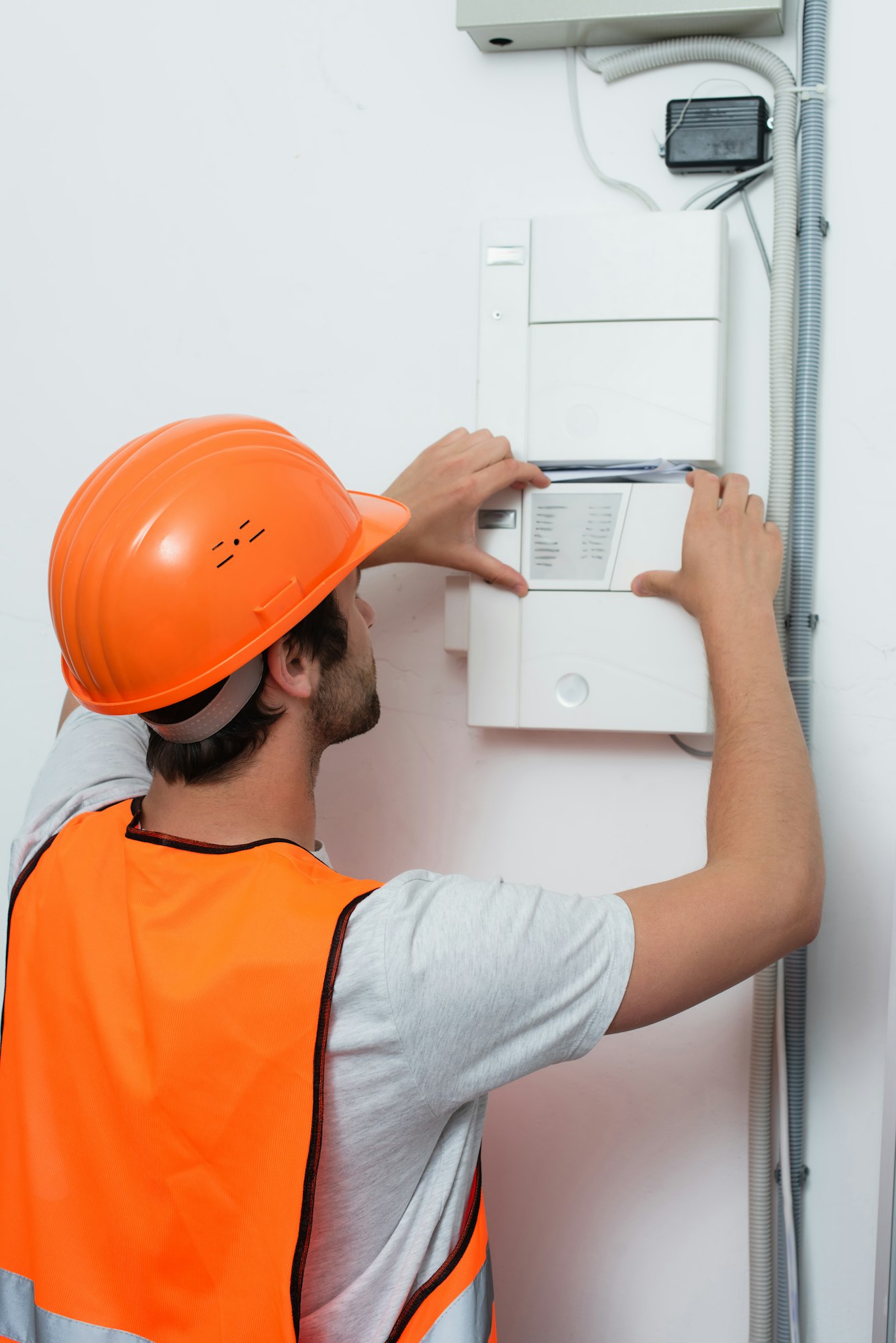 Young repairman in safety vest working with switchboard